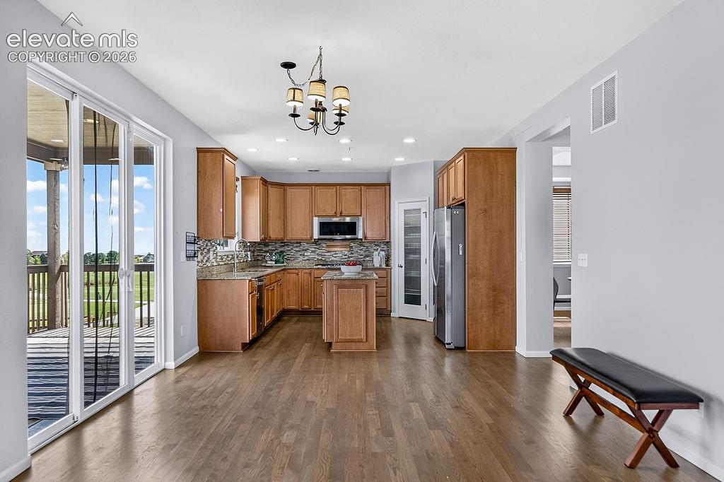 Open-concept kitchen with wood-finish flooring, custom cabinetry, stainless steel appliances, and a central island