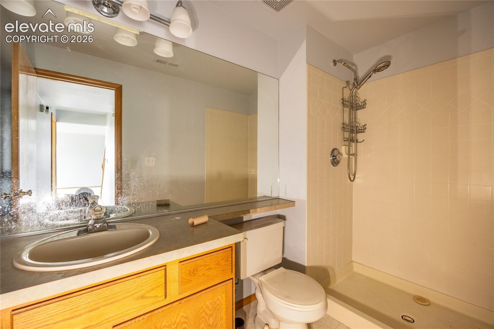 Vanity with an integrated sink, broad counter space, wood-finish cabinetry, and an expansive wall-mounted mirror