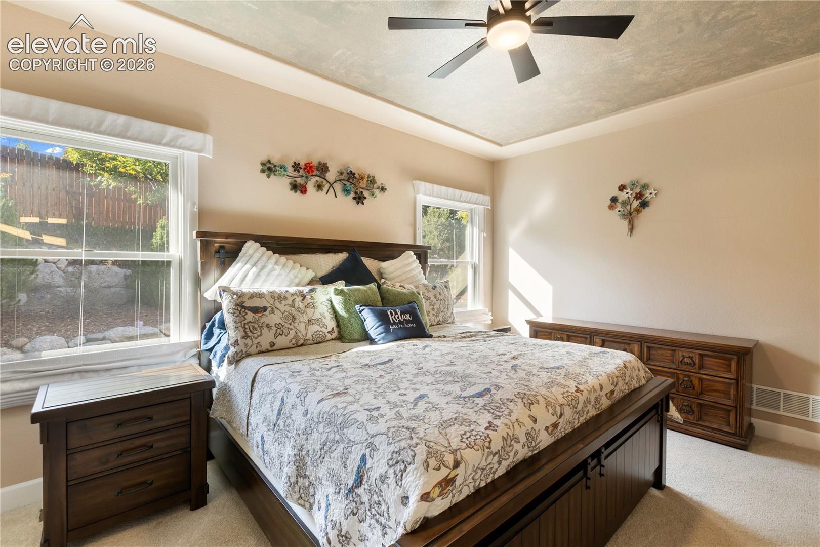 Recessed ceiling with a ceiling fan, two windows, and neutral wall paint