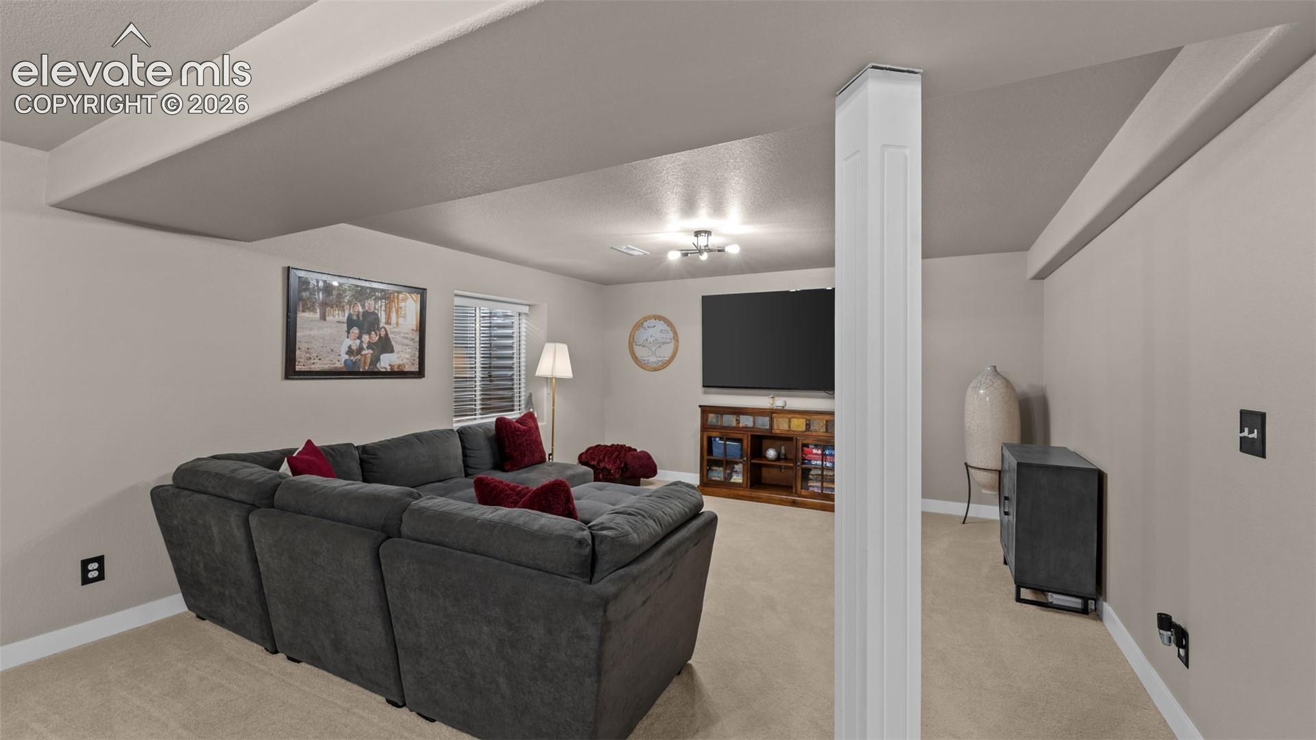 Interior space featuring neutral-toned carpeting, dropped ceiling architecture, a structural support column, and an inset window