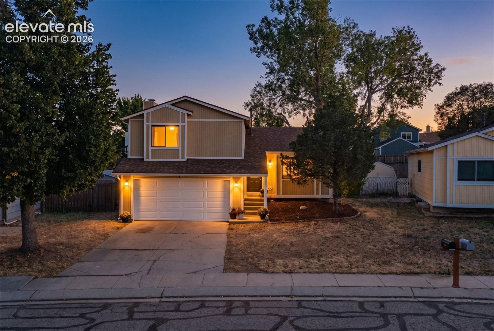 Two-story residence with a two-car garage, mature front yard trees, and a concrete driveway