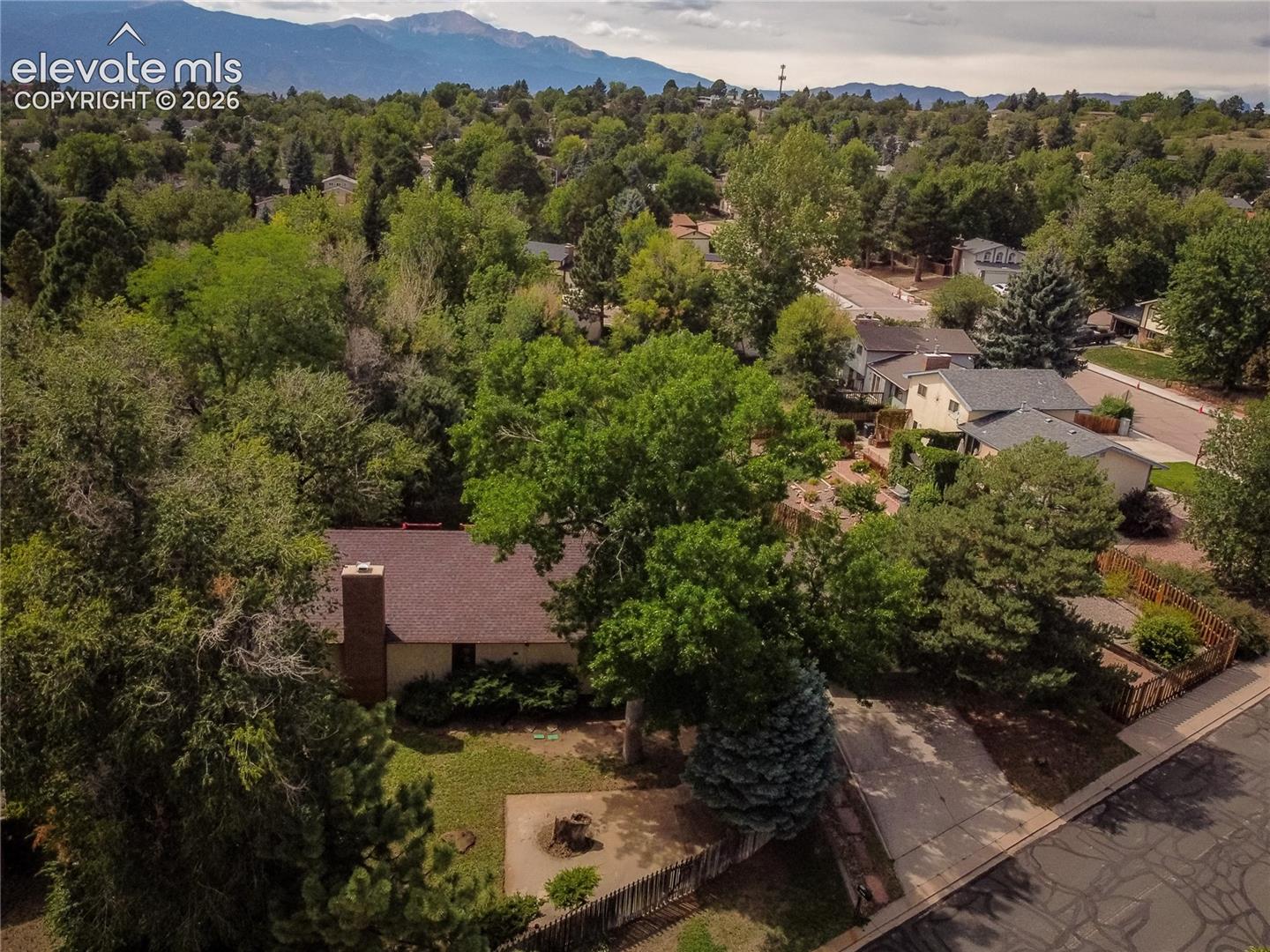 Aerial perspective highlighting the property's expansive green landscaping, mature trees, and paved driveway