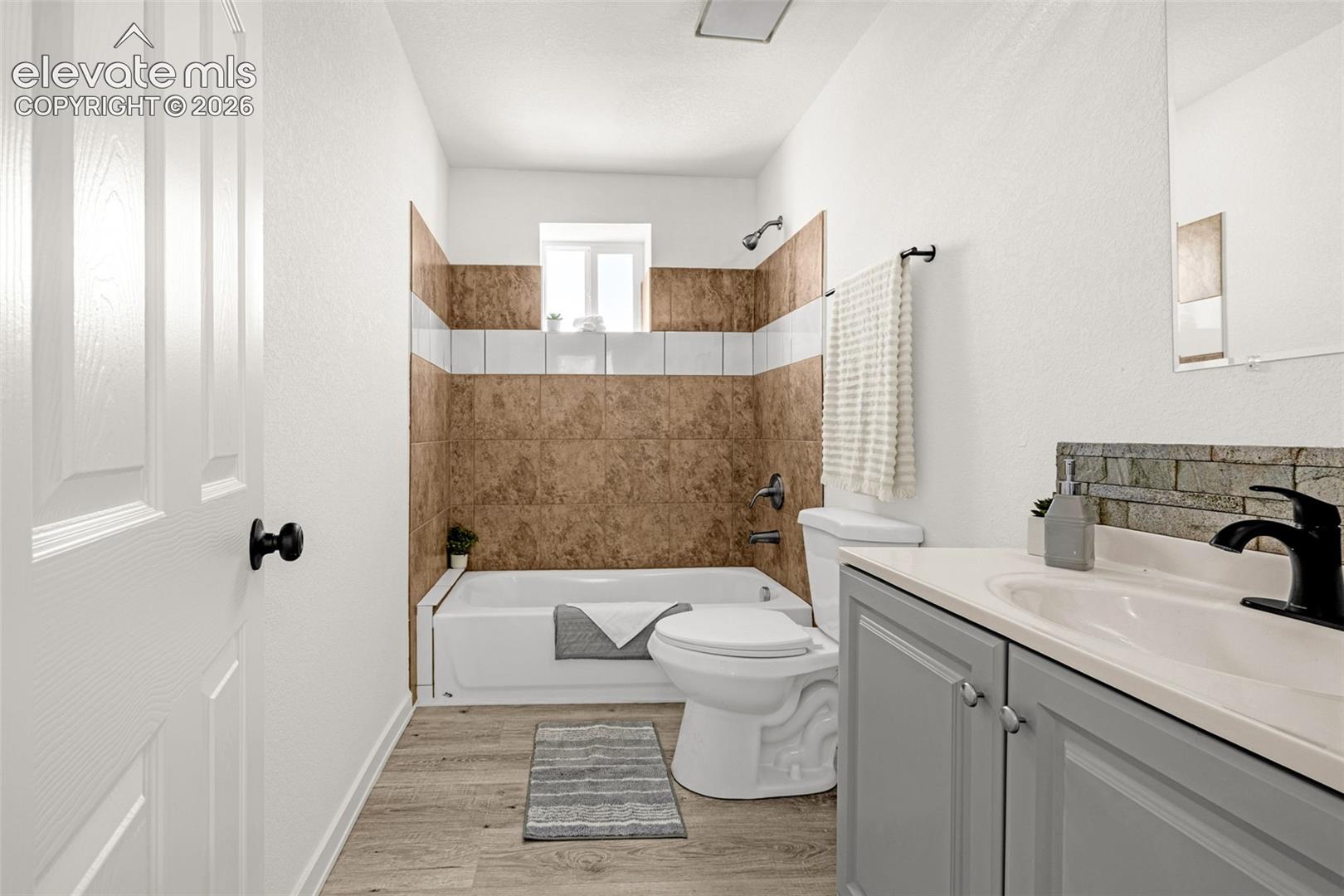 Full bathroom featuring a single vanity with grey cabinetry, a built-in sink, and a black faucet