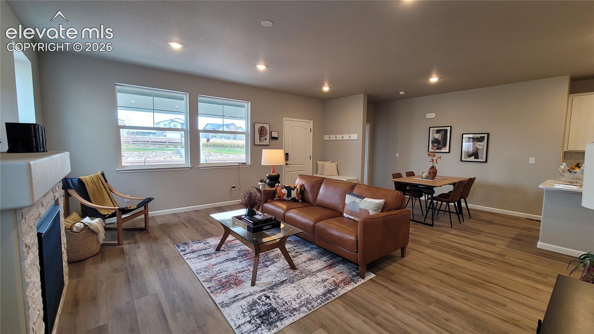 Open-concept interior featuring LVP flooring, LED lighting, and a stacked stone fireplace