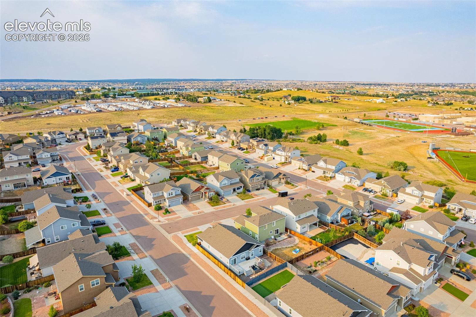 Aerial depiction of a residential neighborhood with varied home styles, paved streets, and surrounding open spaces