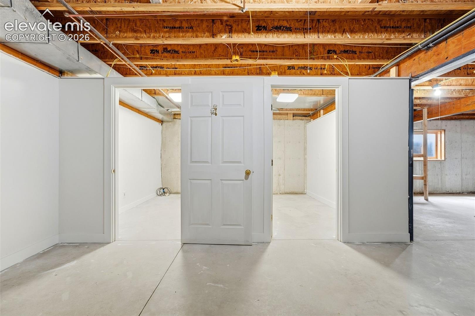 Open unfinished basement offering concrete flooring, exposed wood beams, and framed interior walls