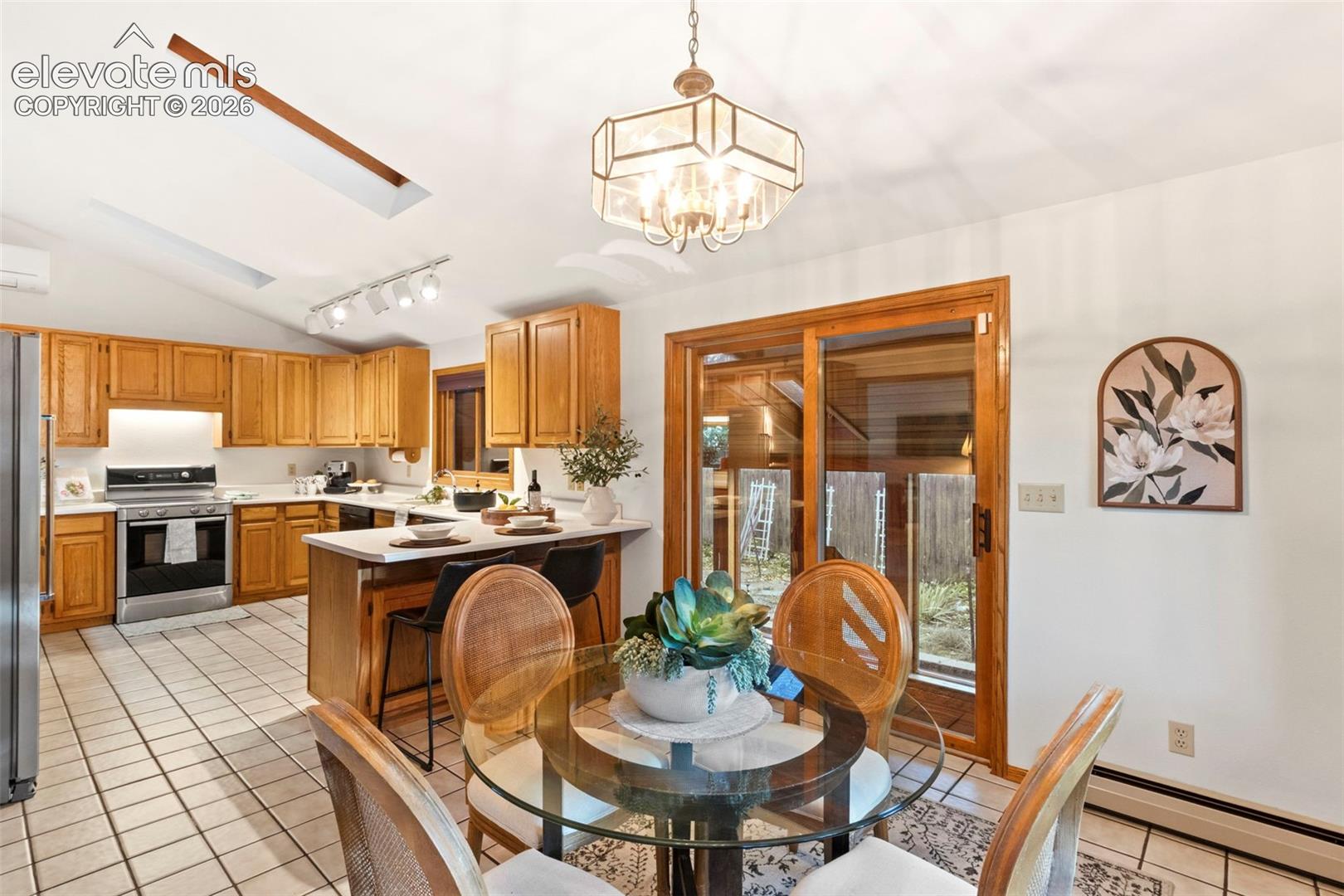 Kitchen featuring wood cabinetry, solid surface countertops, a breakfast bar, skylights, and sliding glass doors