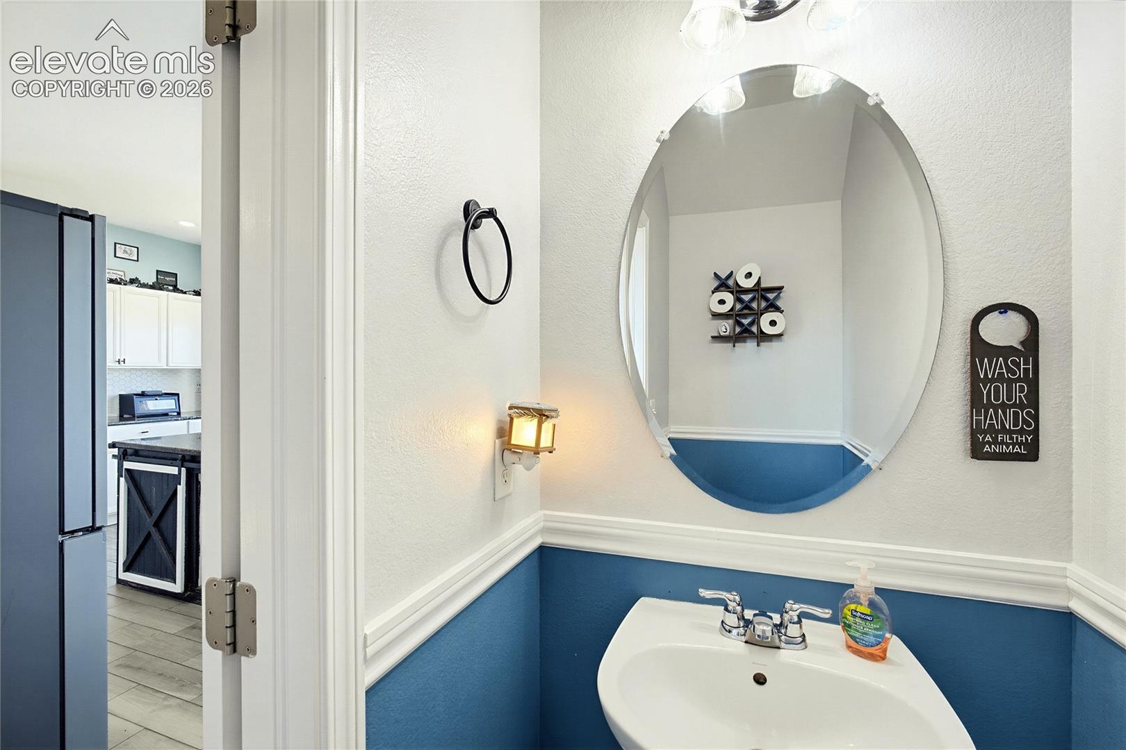 Pedestal sink with chrome fixtures, oval mirror, and wall sconce lighting