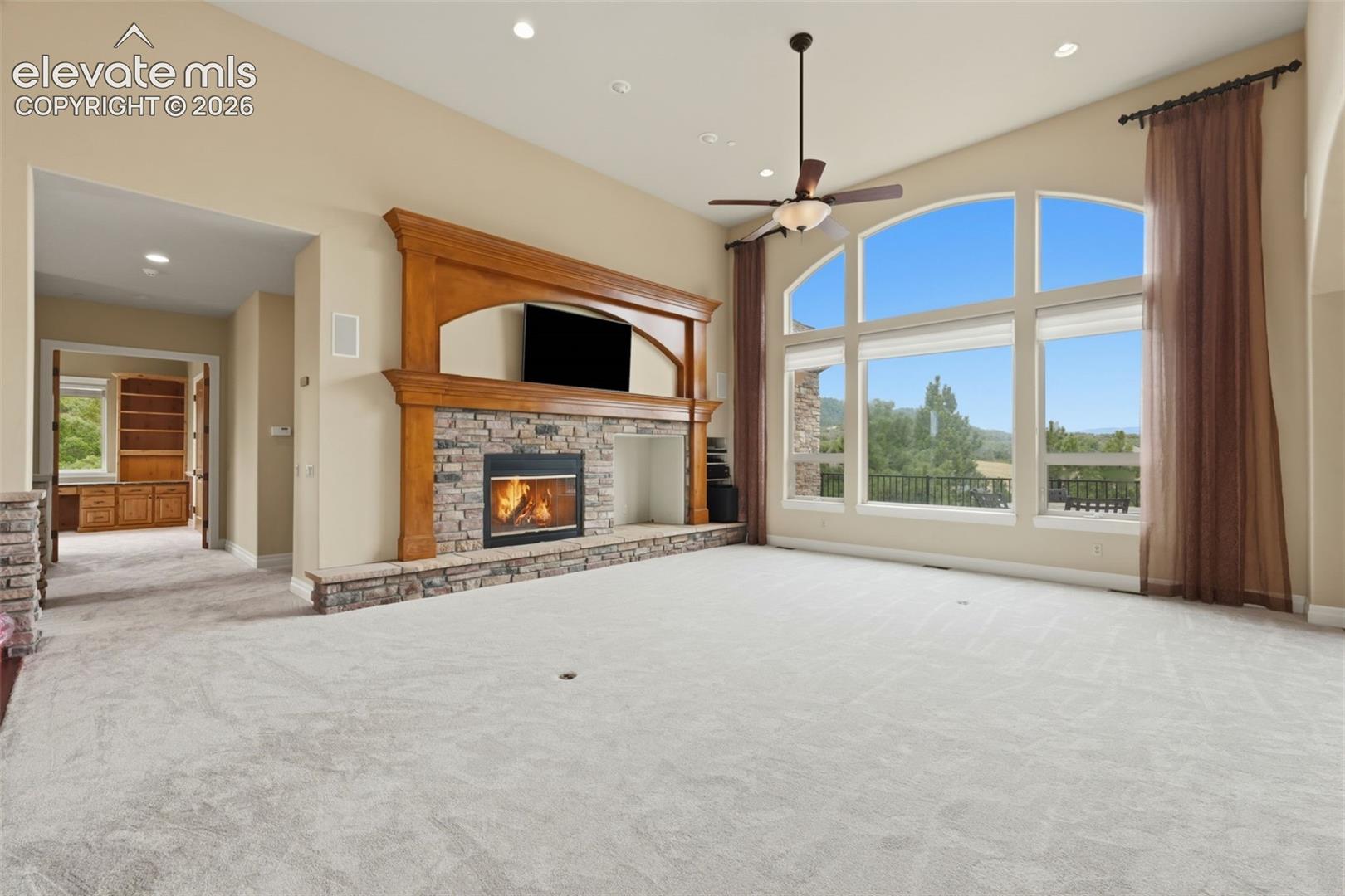Living area featuring a floor-to-ceiling stone fireplace with a wood mantle