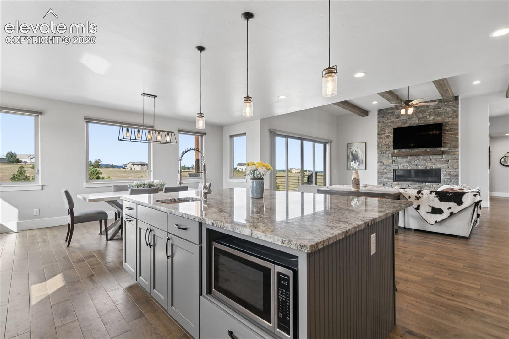 Kitchen island with stone-finish countertop, under-counter microwave, and pendant lighting