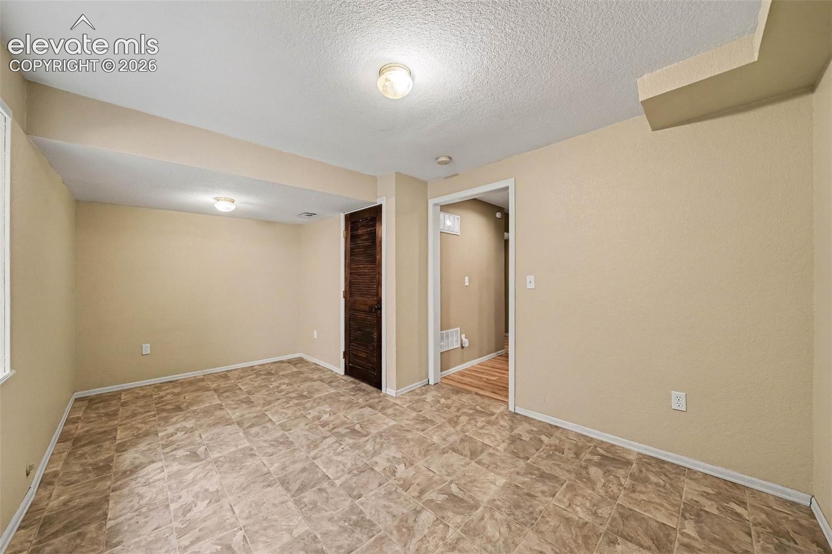 Tile-patterned flooring, recessed lighting, and a wood-finish door