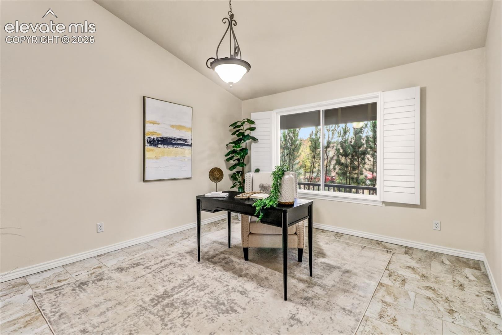 Vaulted ceiling featuring an iron-finish pendant light, large window with plantation shutters, and light-toned tile flooring