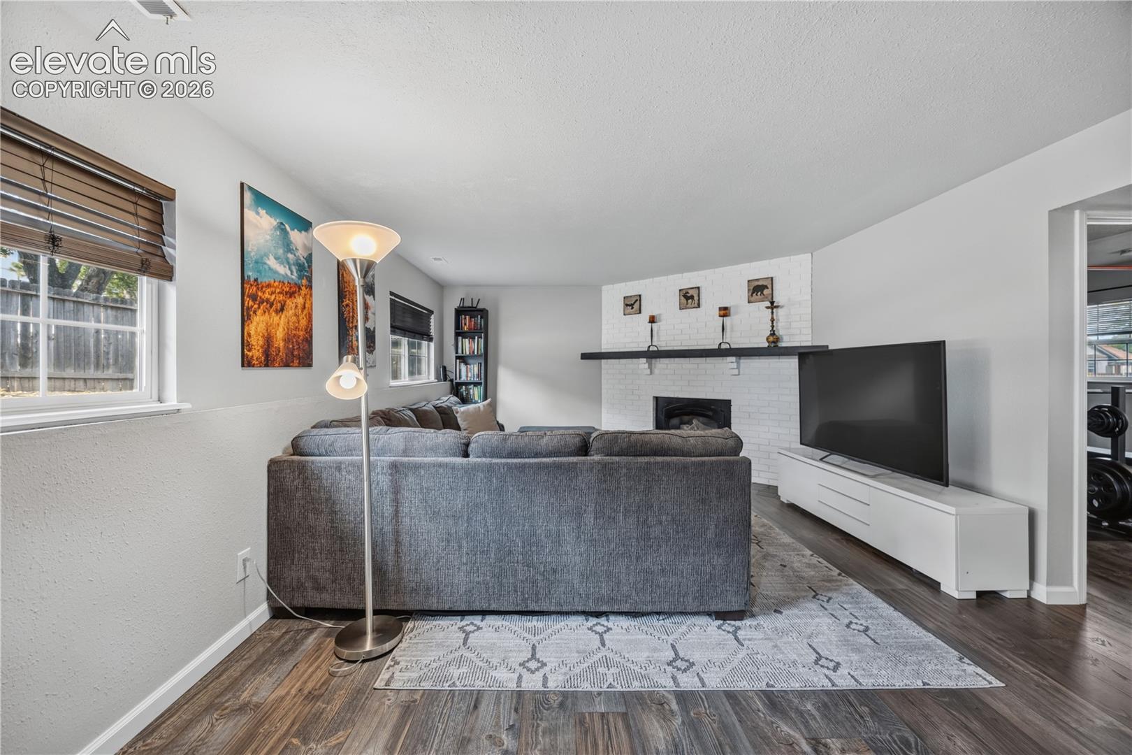Painted brick fireplace with a dark wood-finish mantel and wood-finish flooring throughout