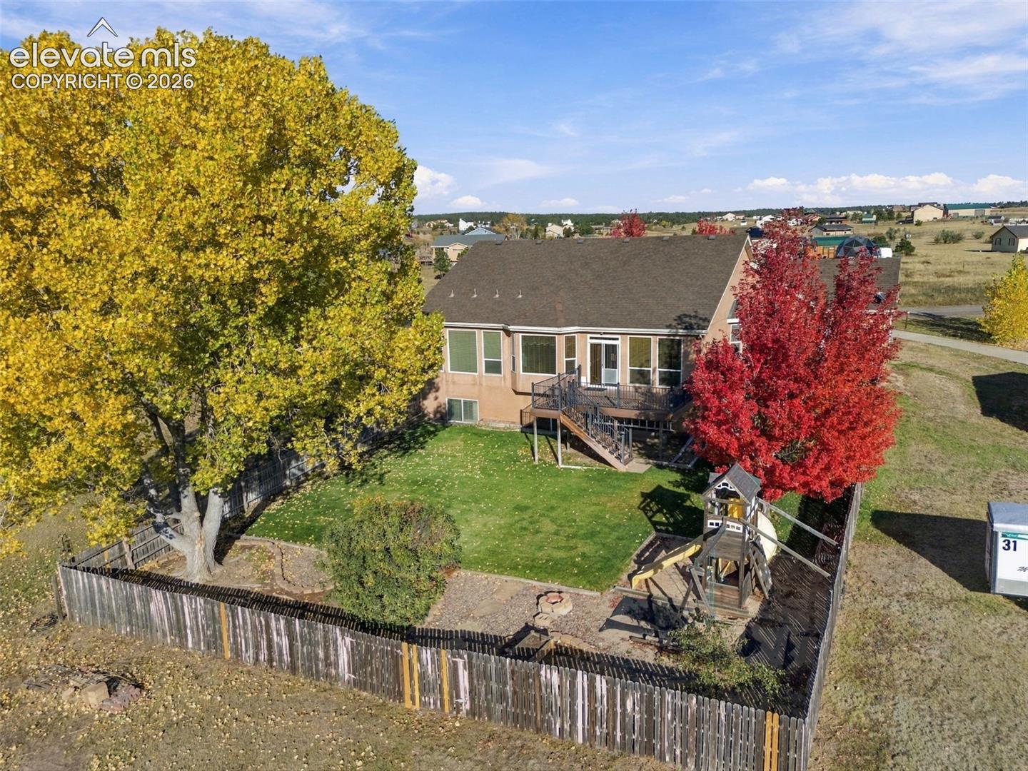 Fully fenced back yard with playset, mature trees and garden area just outside fence with dedicated water.
