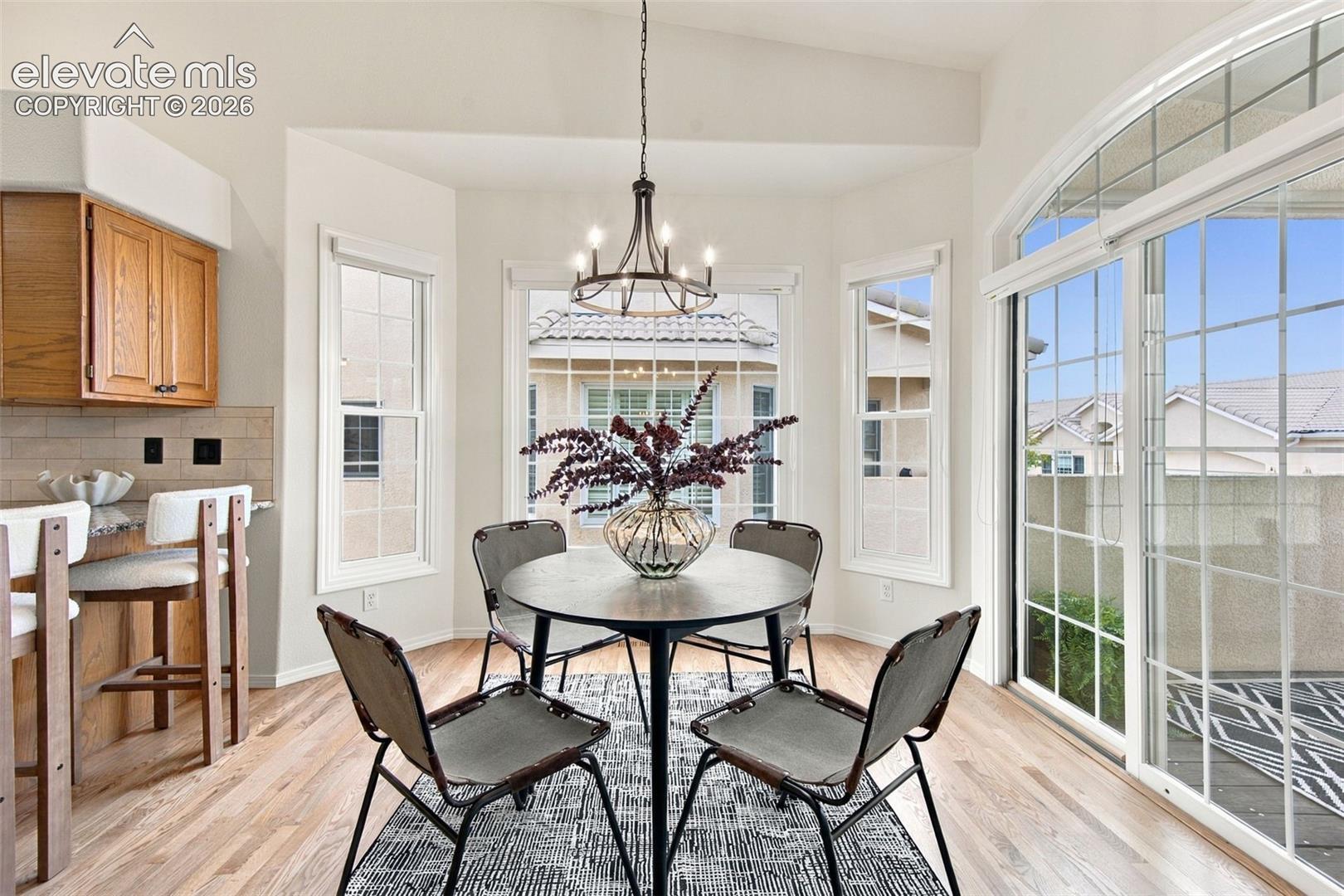 Breakfast nook featuring wood-finish flooring, a decorative chandelier, multiple windows, and a sliding glass door with a grid pattern