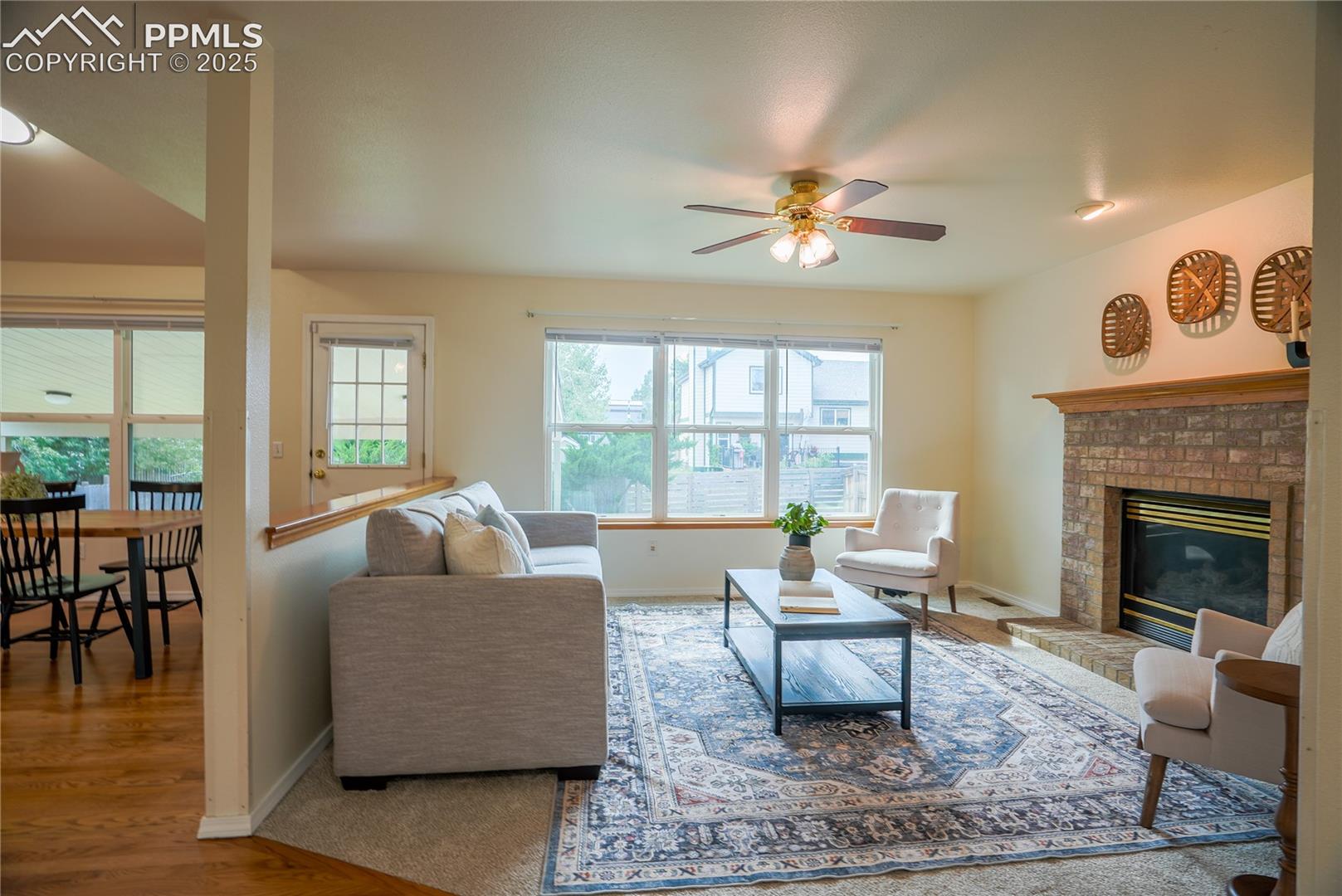 Living room with a brick fireplace, and a ceiling fan