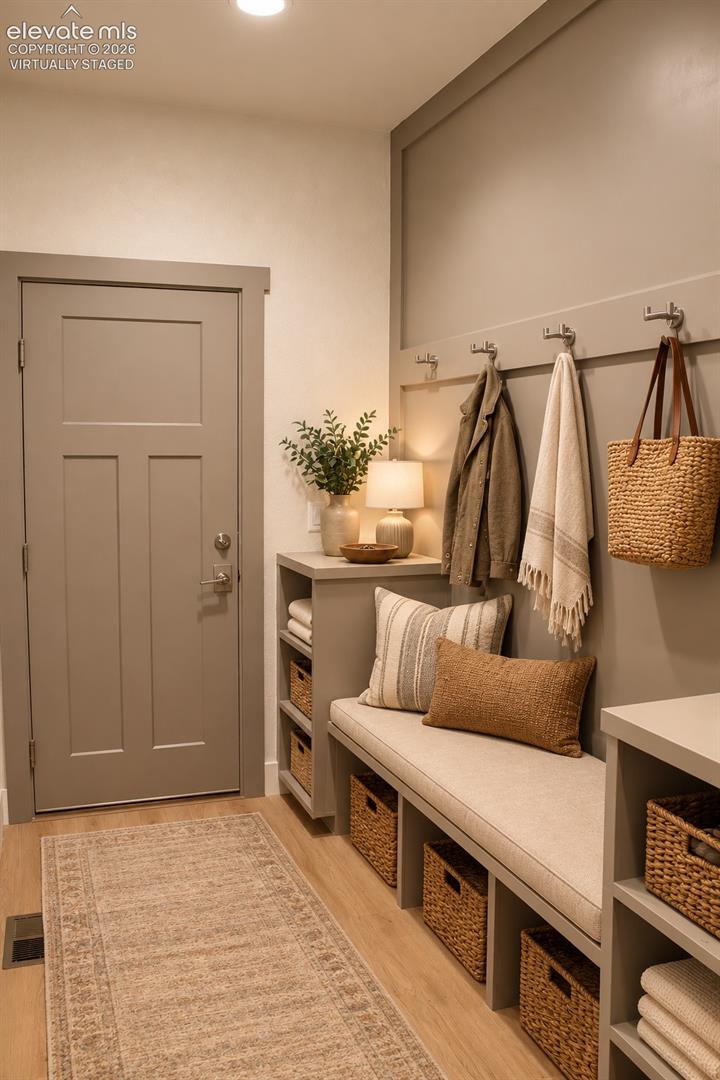 Virtually staged Built-in bench with integrated storage cubbies, wall-mounted coat hooks, wood-finish flooring, recessed ceiling lighting, and a solid-panel door