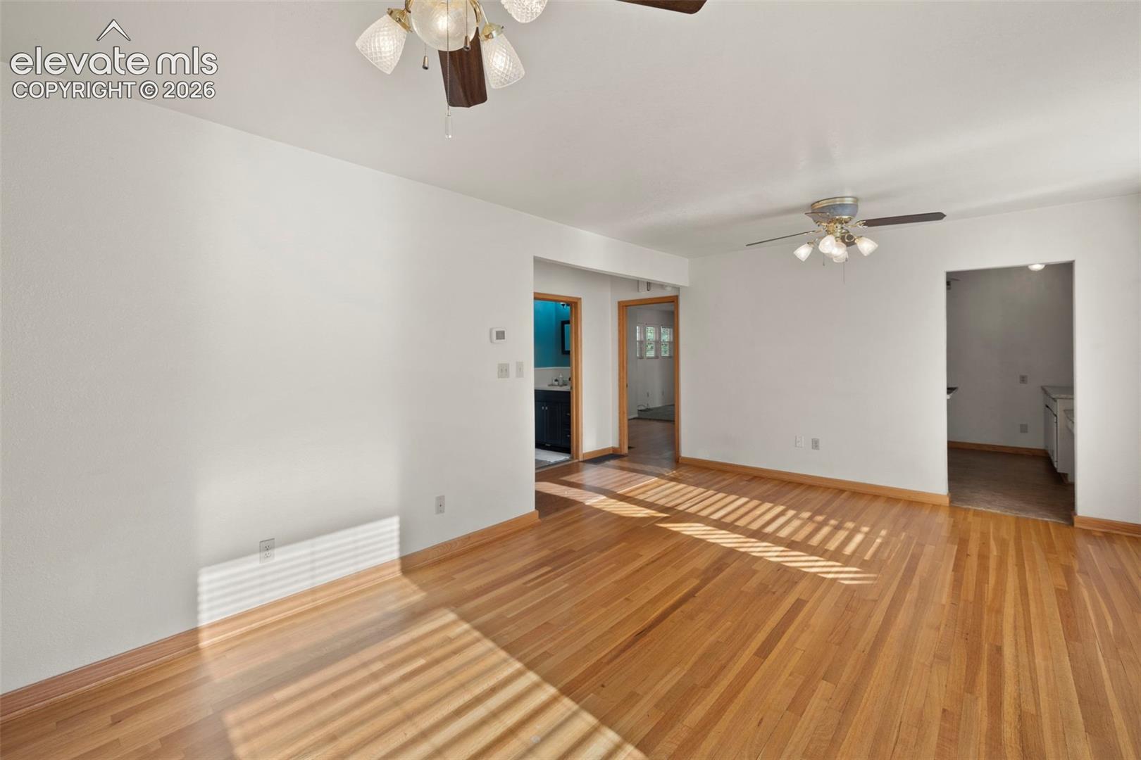Hardwood flooring, white walls, and ceiling fans with integrated lighting