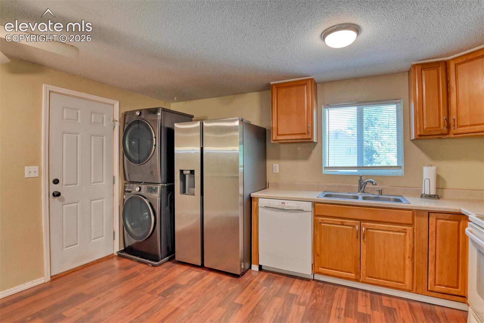 Kitchen area with wood-finish flooring, light-toned cabinetry, and a double basin sink