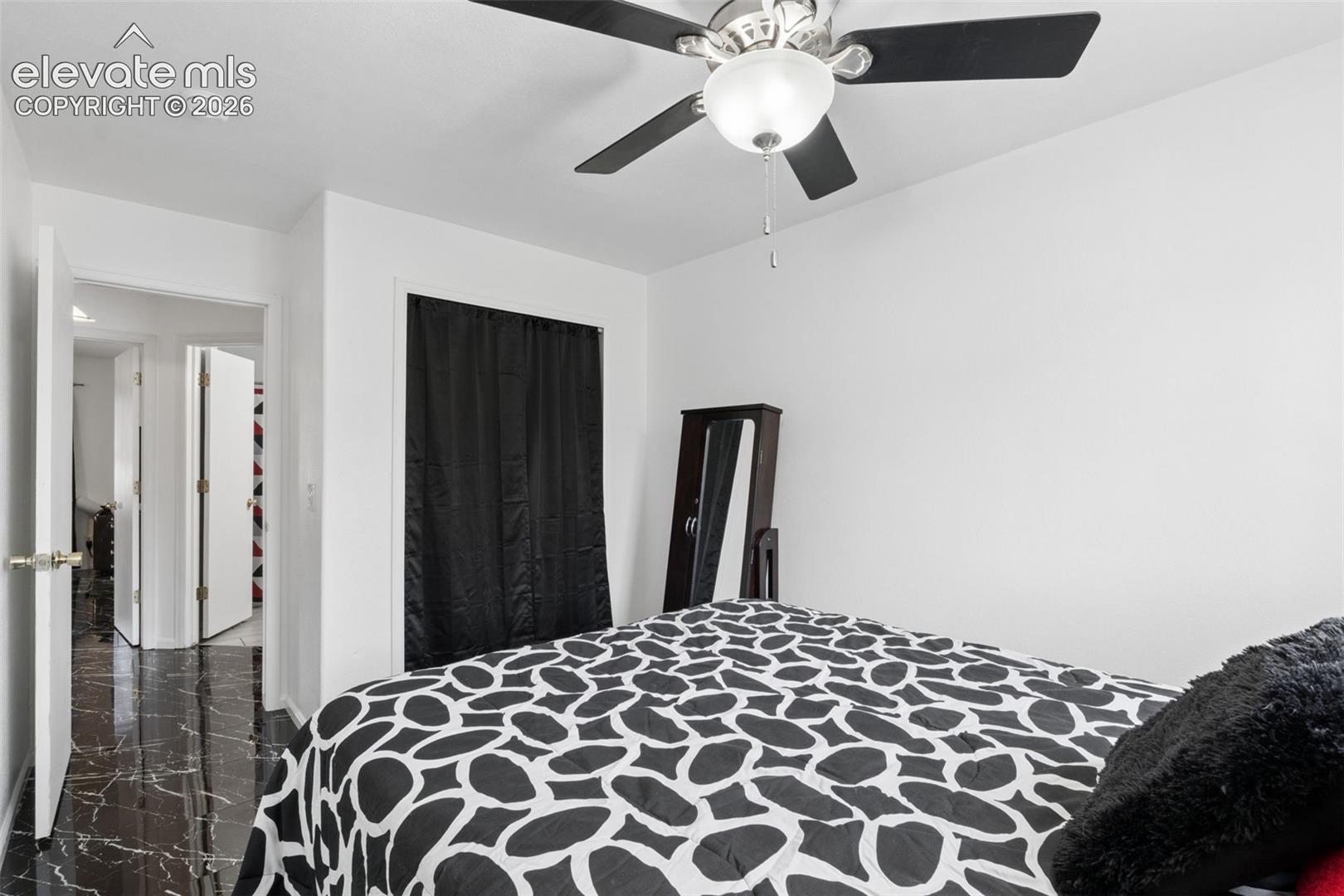 Black marble-finish flooring, white walls, and a ceiling fan with integrated lighting