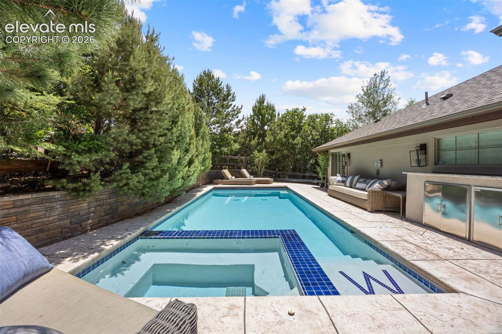 Outdoor swimming pool featuring a built-in spa with blue tile accents