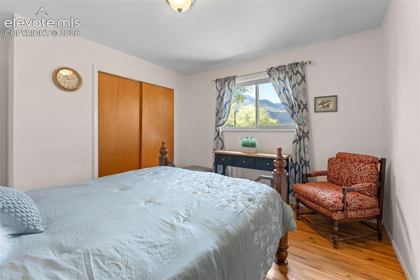 Hardwood flooring, wood-finish sliding closet doors, ceiling-mounted light fixture, and a window with mountain scenery