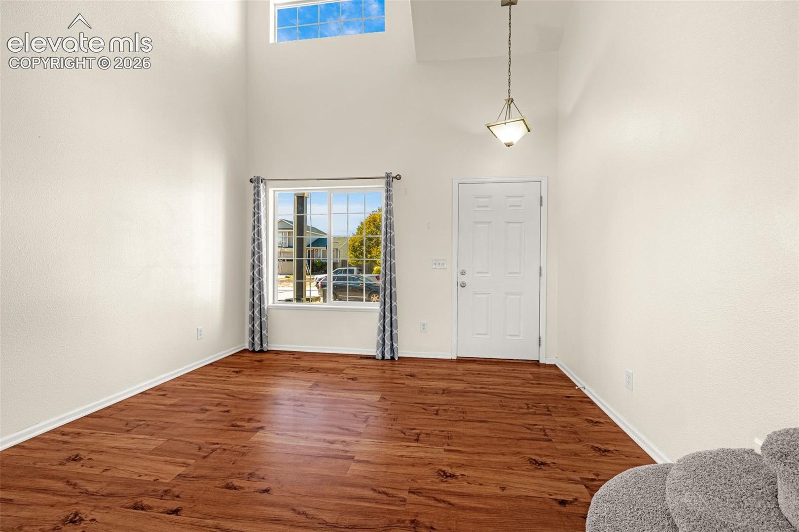 High ceilings featuring a clerestory window, wood-finish flooring, and a pendant light fixture
