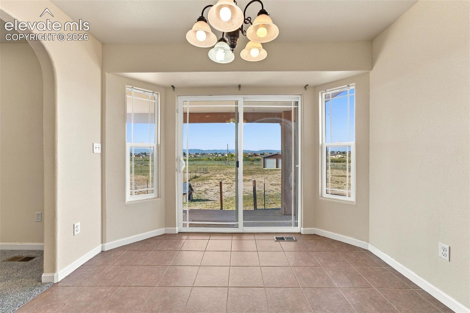 Bay area featuring ceramic tile flooring, five-light chandelier, sliding glass doors, and arched architectural detailing