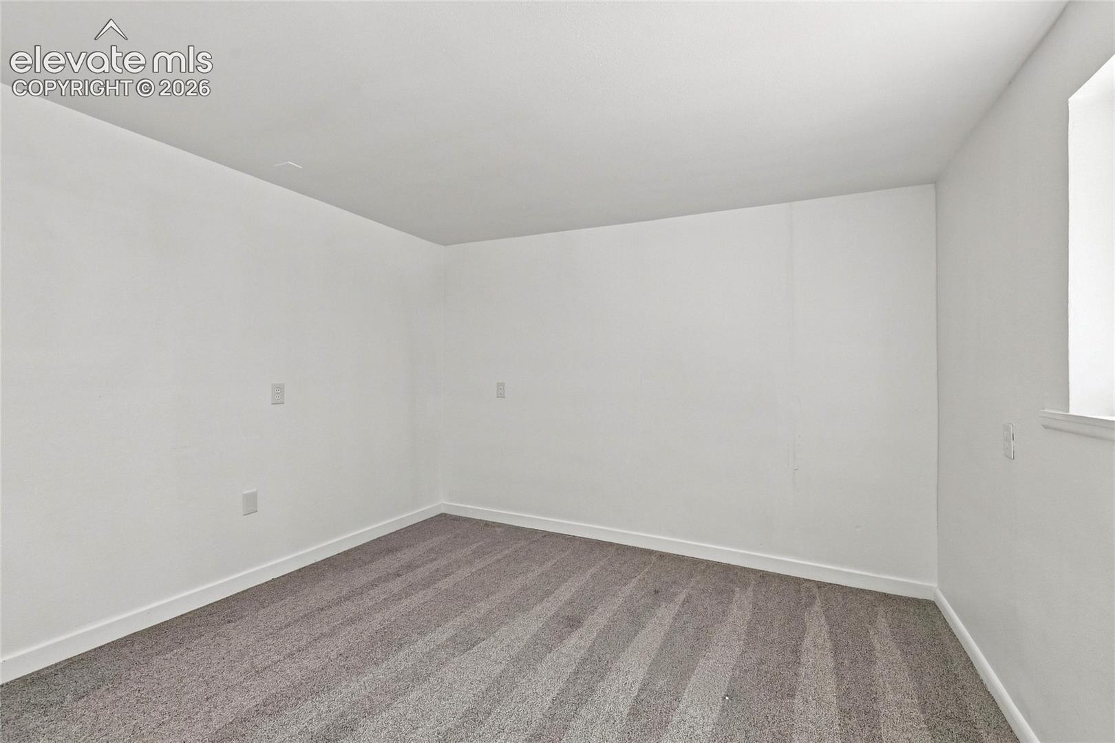 Neutral wall color, wall-to-wall carpeting, and a single window