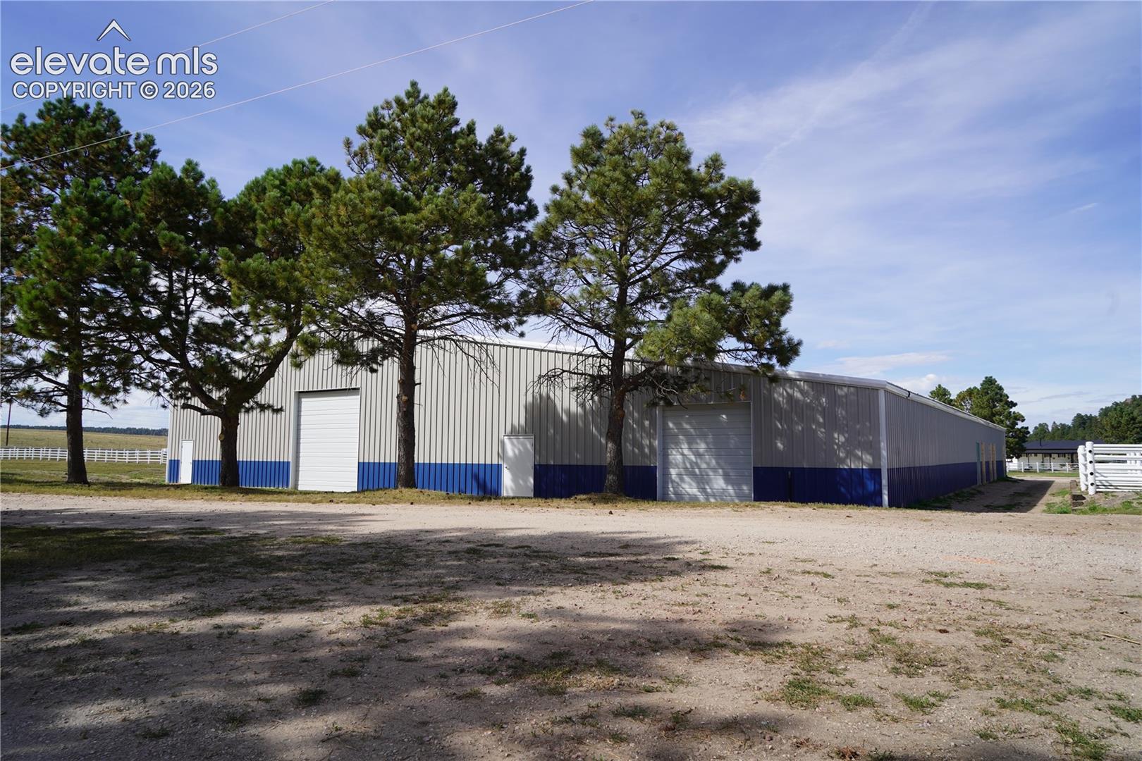 Arena - Expansive metal building featuring a pitched roof, multiple entry doors, a large roll-up door, and a two-tone exterior