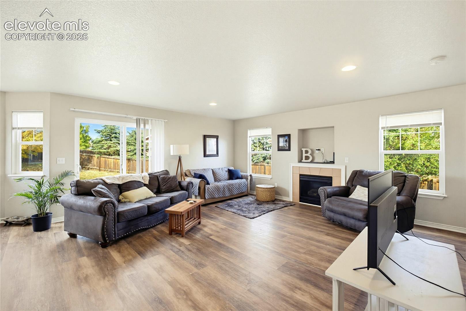 Living area featuring wood-finish flooring, recessed lighting, a built-in fireplace, and expansive windows