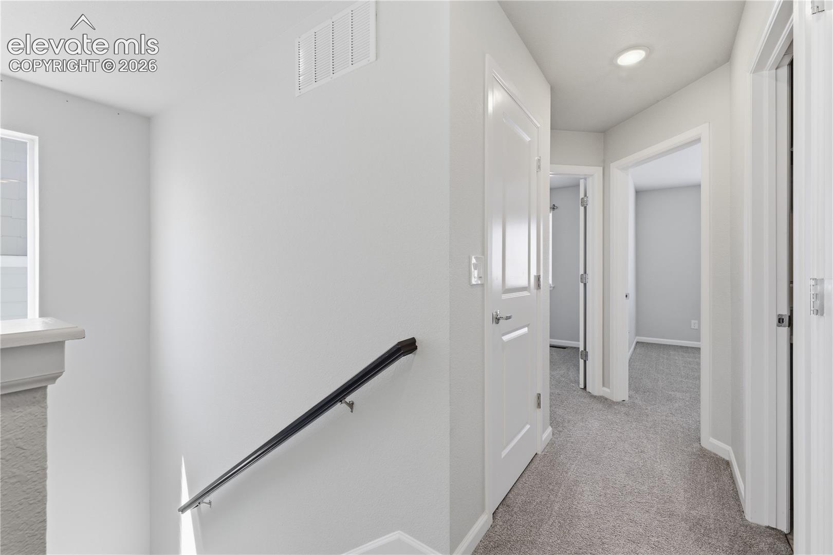 Upper-level hallway with neutral carpeting and recessed lighting