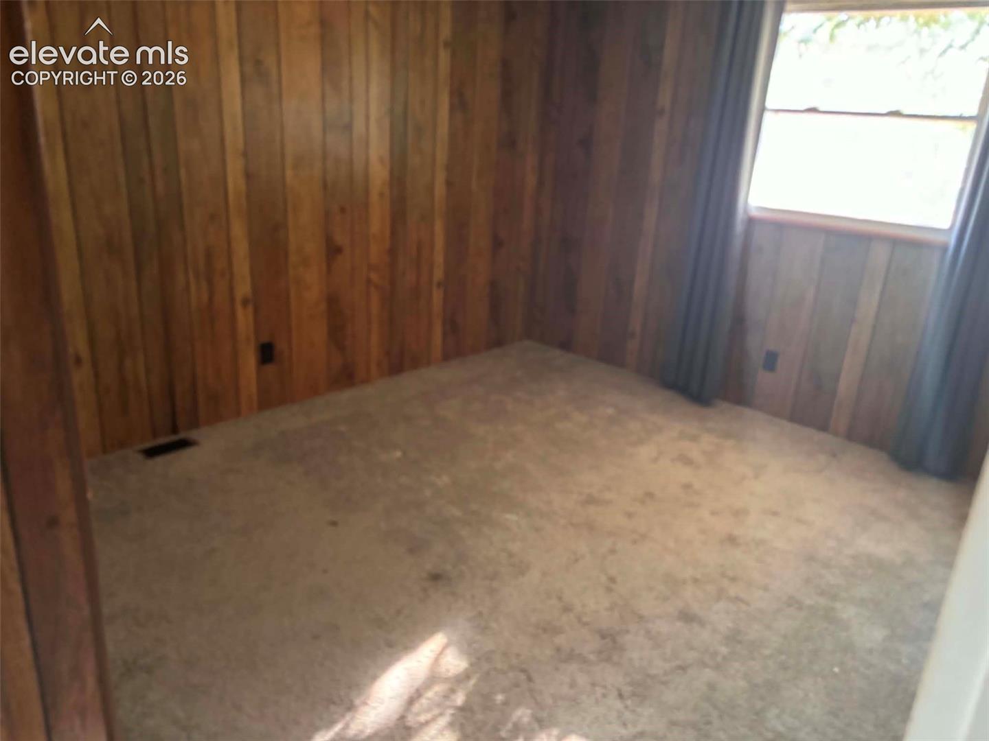 Interior room featuring vertical wood paneling and a multi-pane window