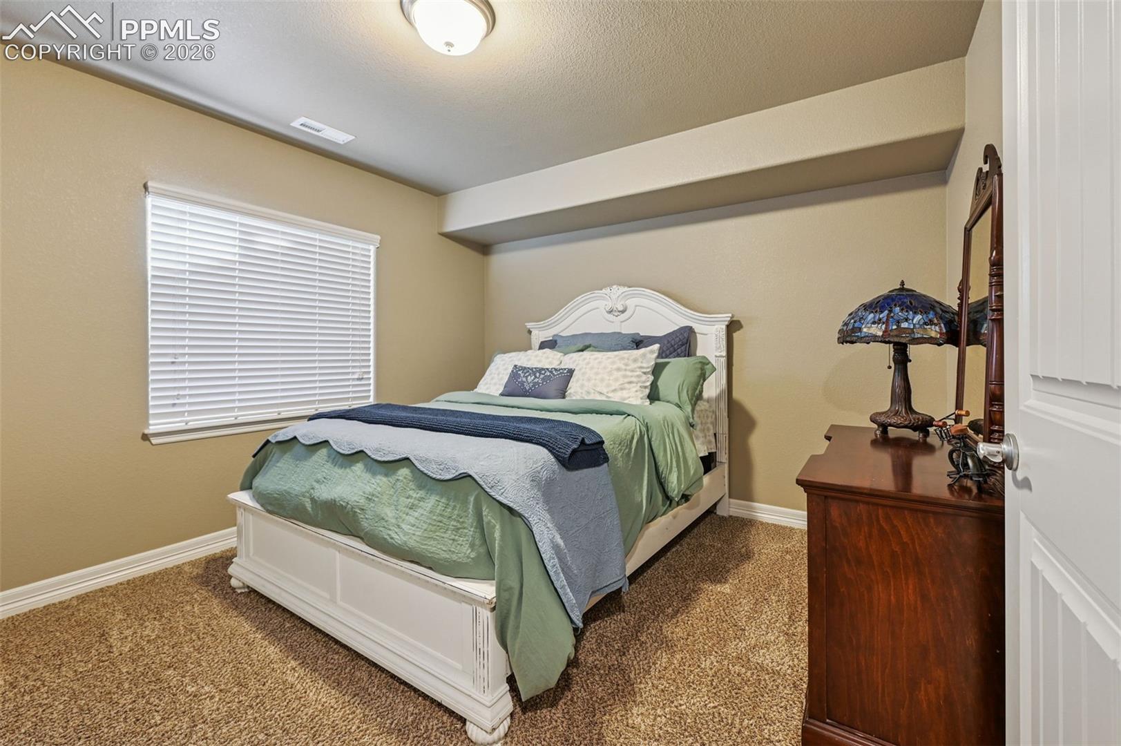 Carpeted bedroom featuring baseboards and a textured ceiling