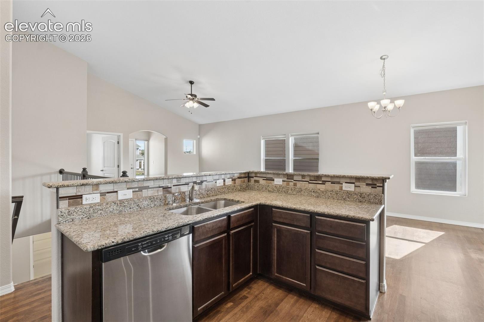 Kitchen featuring an L-shaped peninsula with granite-finish countertops, stainless steel sink, and stainless steel dishwasher