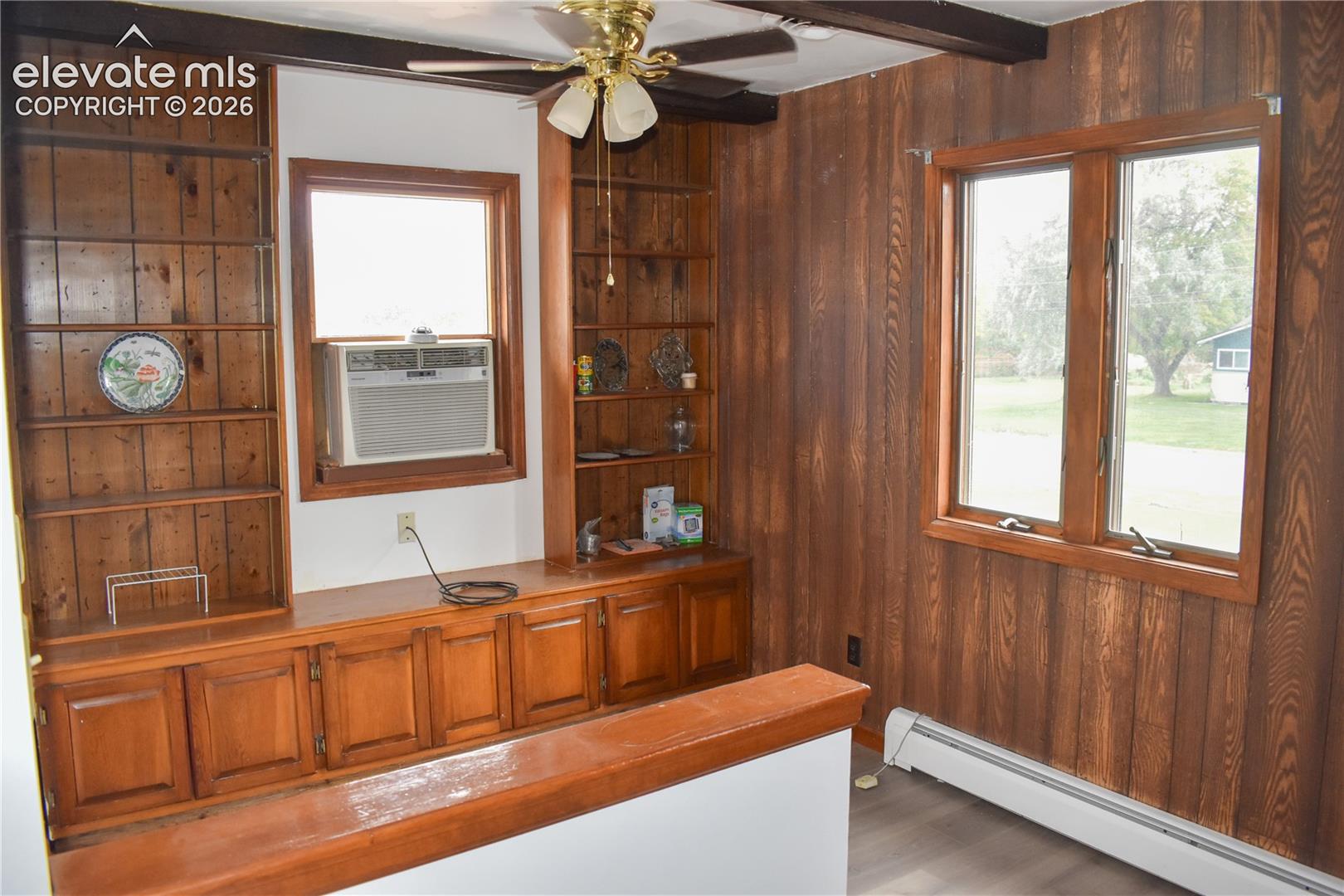 Built-in wood shelving and cabinetry, wood paneling, exposed ceiling beams, and wood-finish flooring
