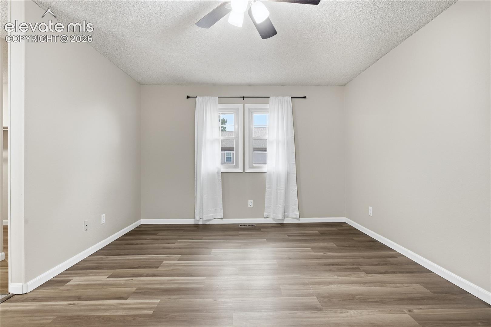 Neutral wall color, wood-finish flooring, and a ceiling fan