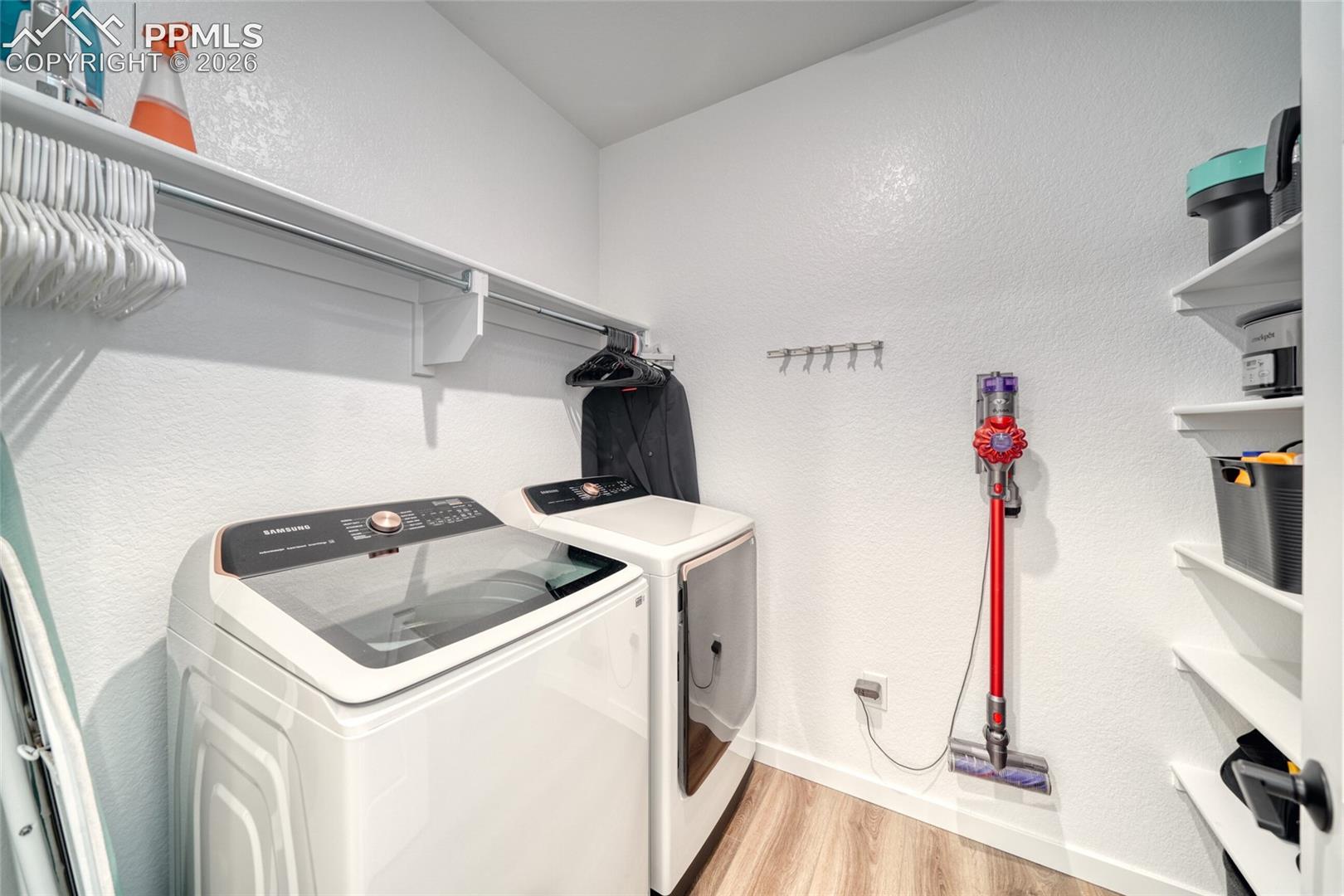 Laundry room featuring a textured wall, light wood-style floors, and washer and clothes dryer