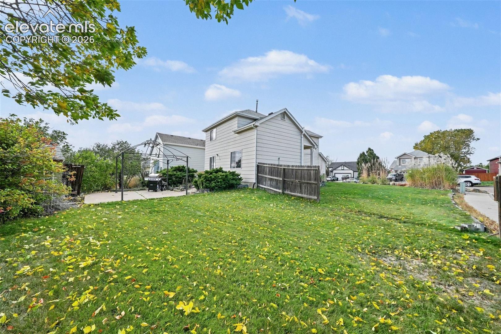 Rear yard featuring a lawn, concrete patio, and wood privacy fencing