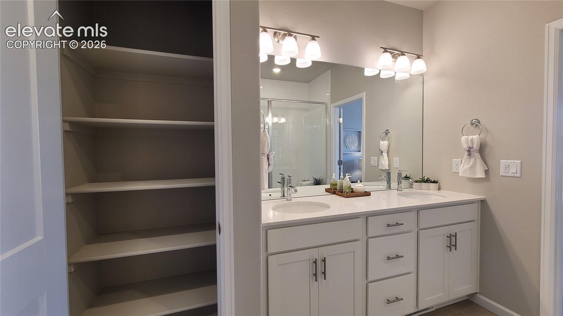 Primary 3/4 Bathroom with double vanities, shower with bench and tile surrounds, cabinet/drawer pulls, quartz countertop, and linen closet! 