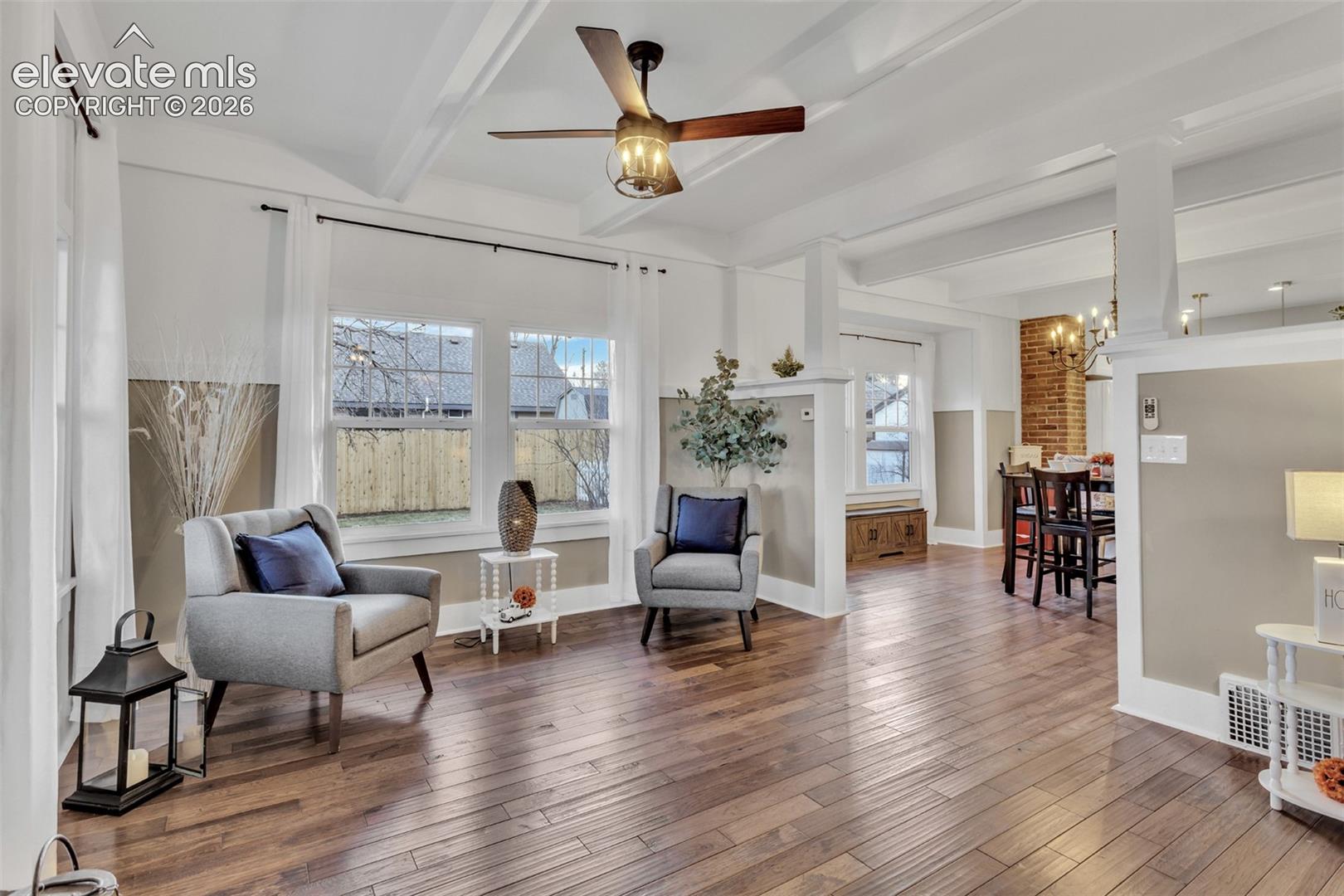 Open-concept living space featuring wood-finish flooring, white coffered ceilings, and a modern ceiling fan