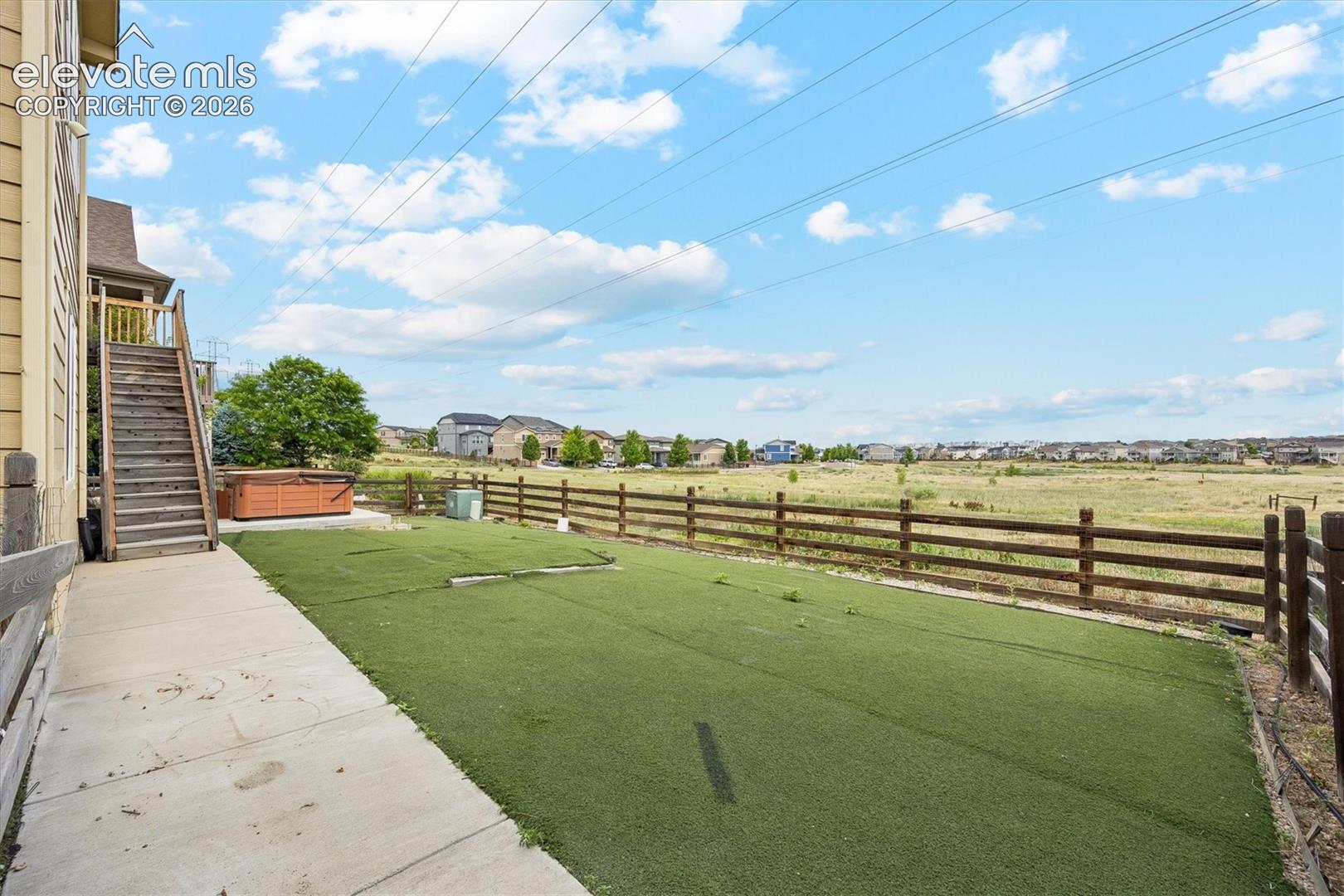 Expansive backyard featuring artificial turf, a concrete patio, and a wood plank fence