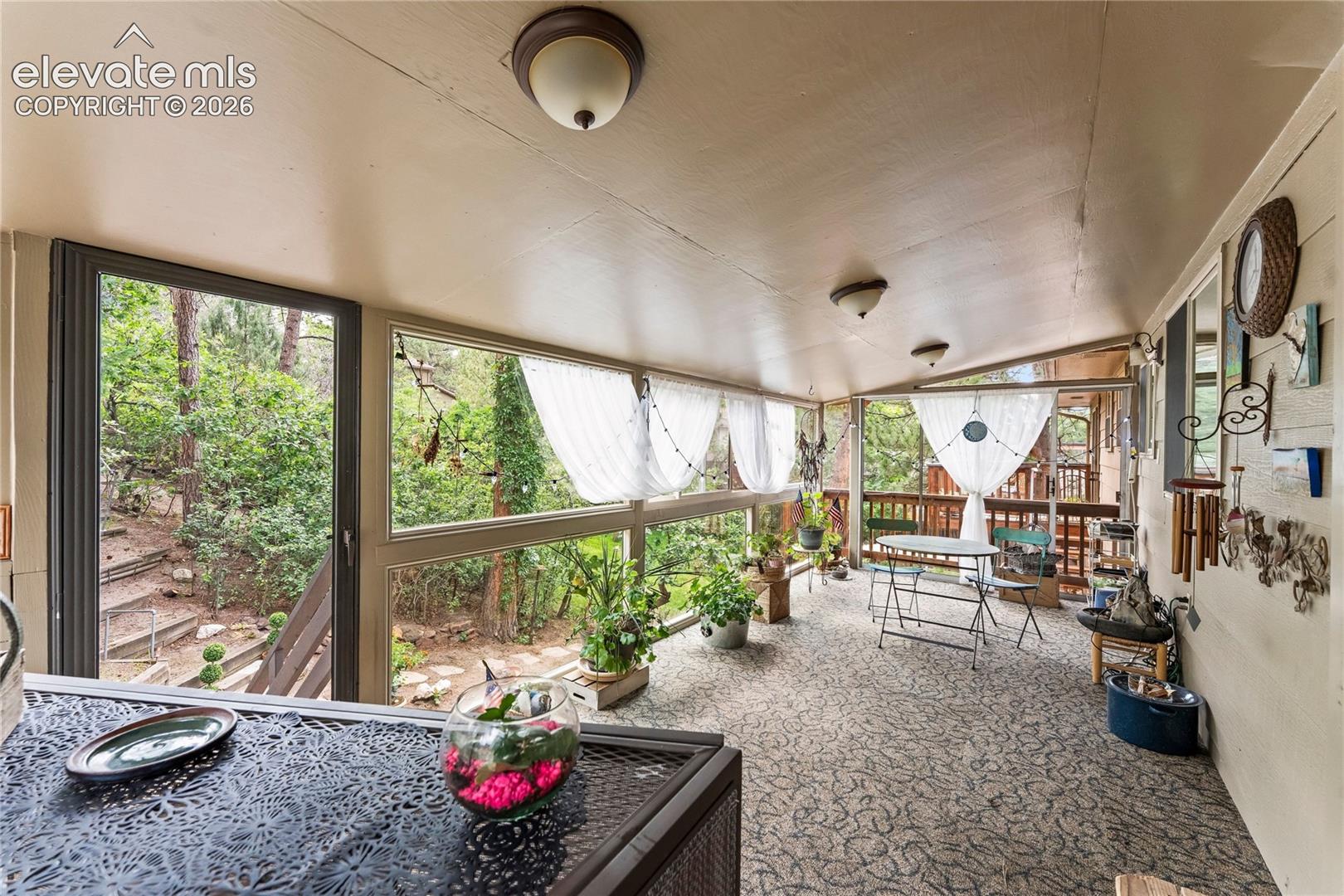 Enclosed patio featuring a patterned floor, multiple windows, and a wood ceiling