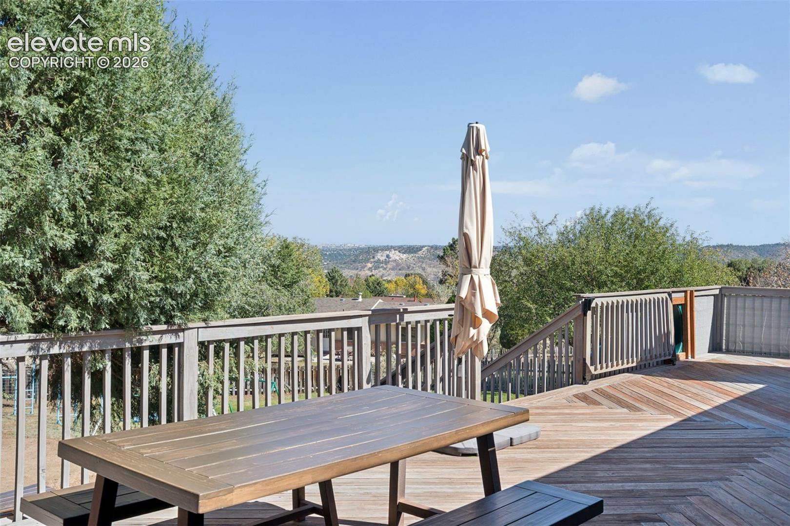 Expansive elevated deck featuring herringbone-pattern wood-finish decking, perimeter wood railings, and stairs
