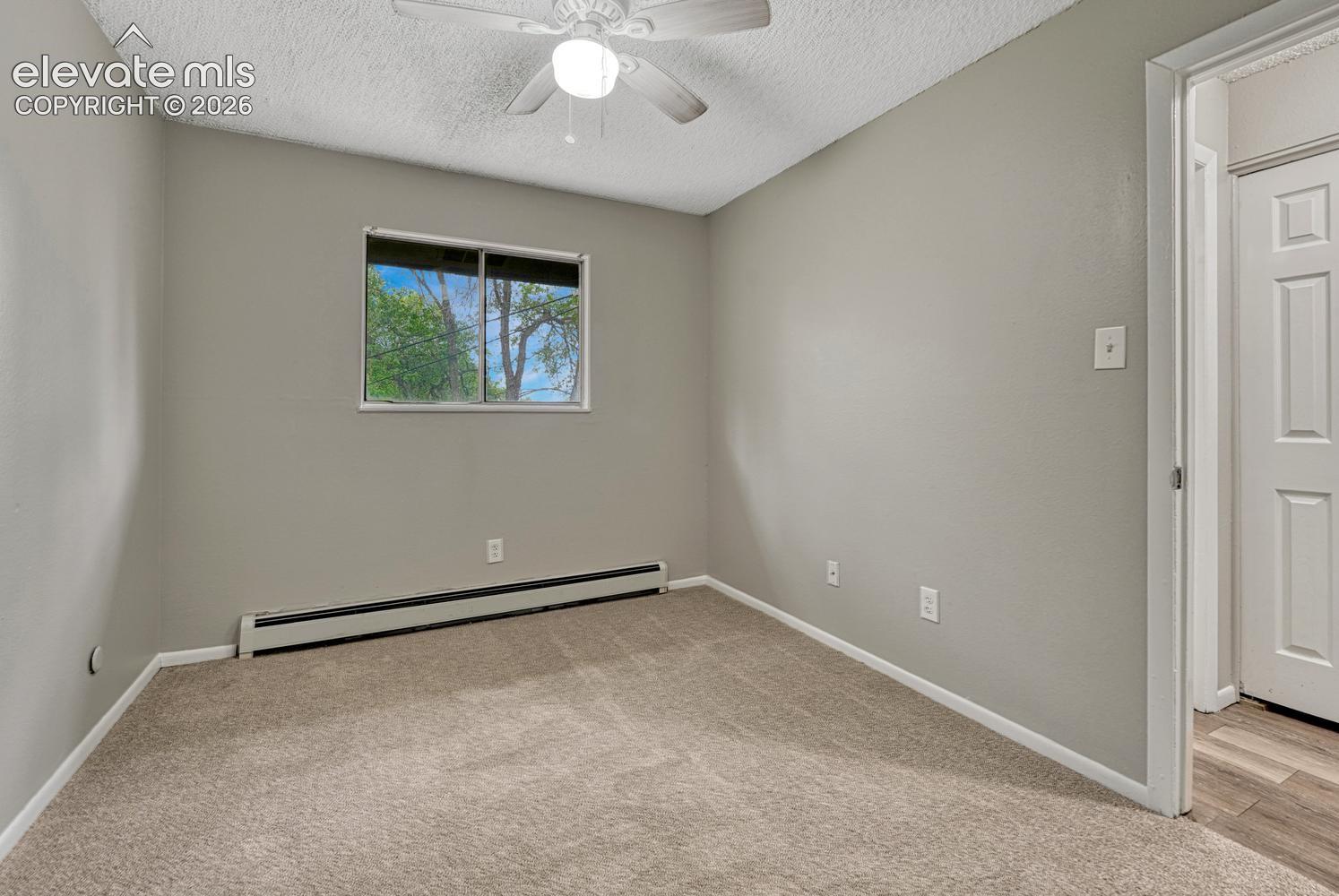 Recessed window, textured ceiling, ceiling fan with light fixture, gray wall paint, and light-toned carpet flooring