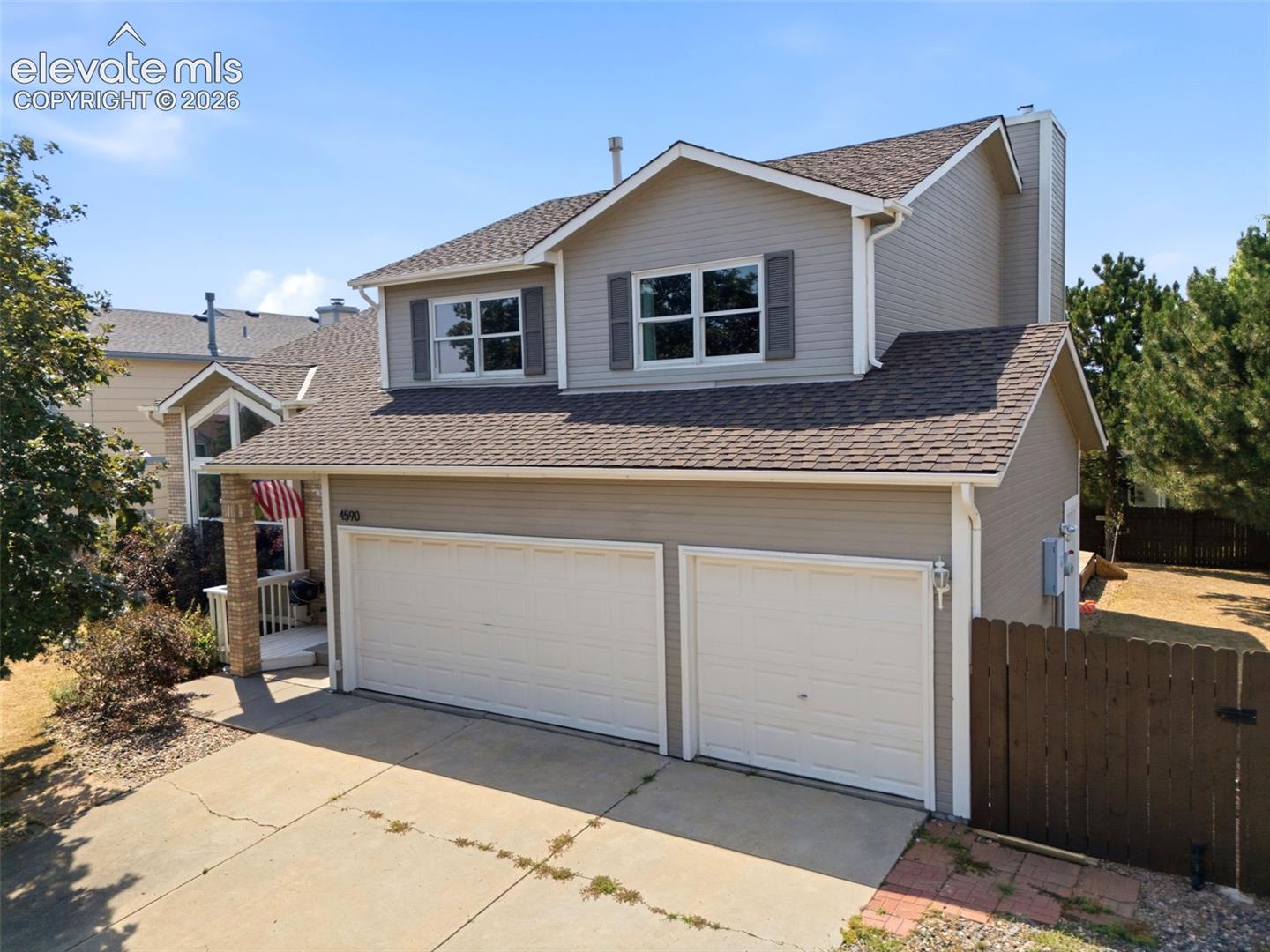 Two-story residence with a two-car garage, gray siding, and a brown shingle roof