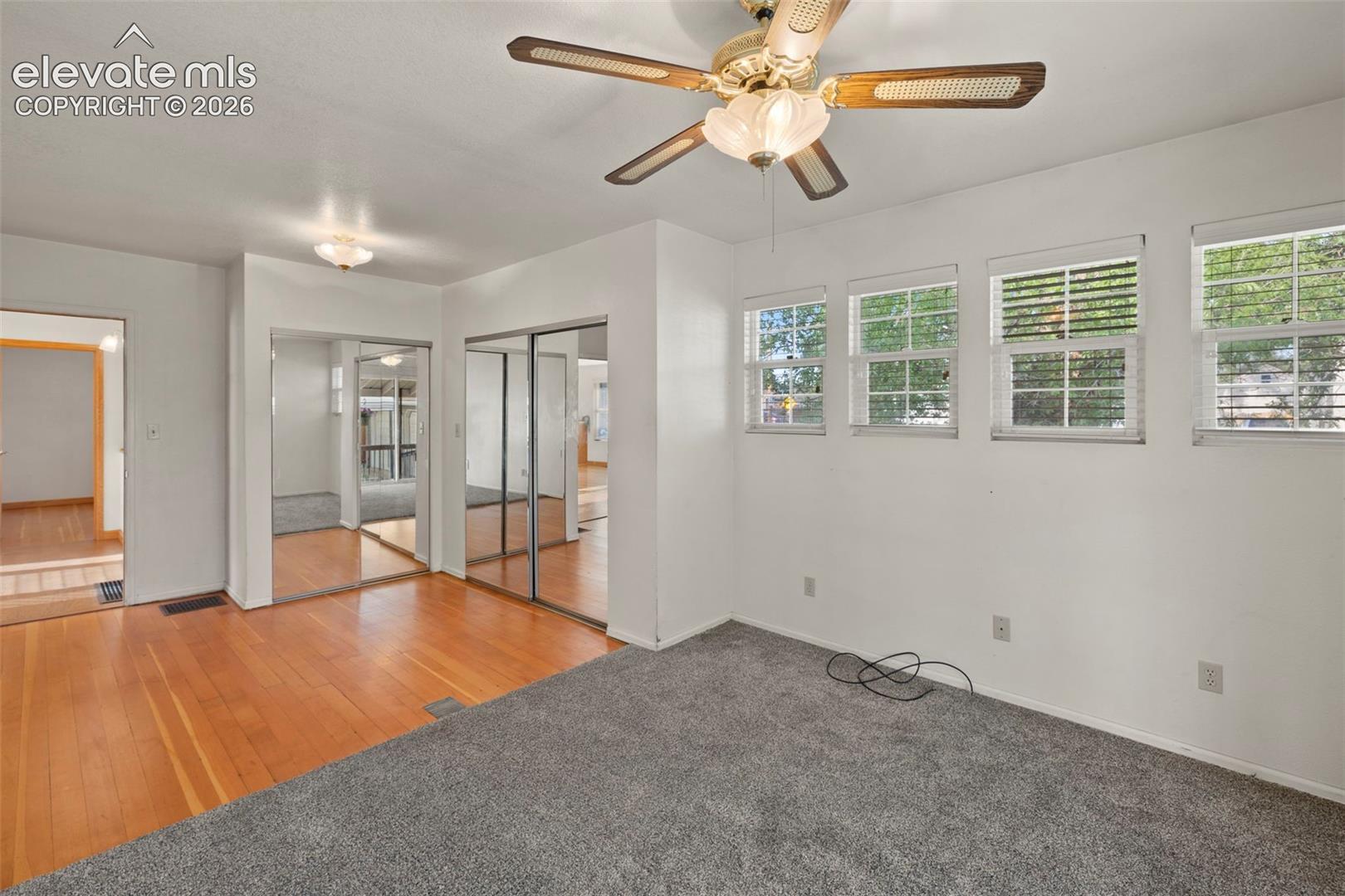 Recessed lighting, ceiling fan light fixture, wood-finish flooring, mirrored closet doors, and multiple windows