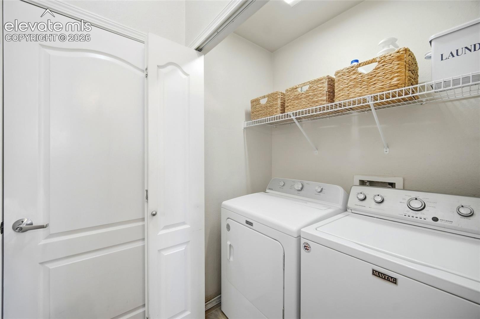 Laundry area featuring a wire storage shelf, white wall paint, and white trim
