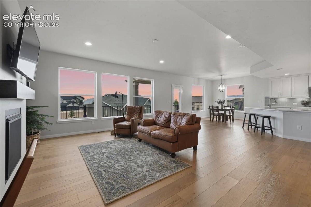 Open-concept living area featuring light wood-finish flooring, recessed lighting, and a built-in fireplace