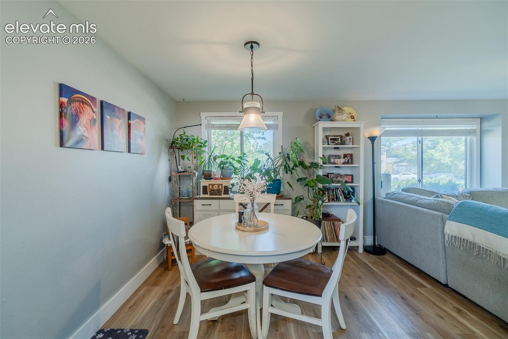 Dining area featuring wood-finish flooring, a pendant light fixture, and abundant natural light from multiple windows